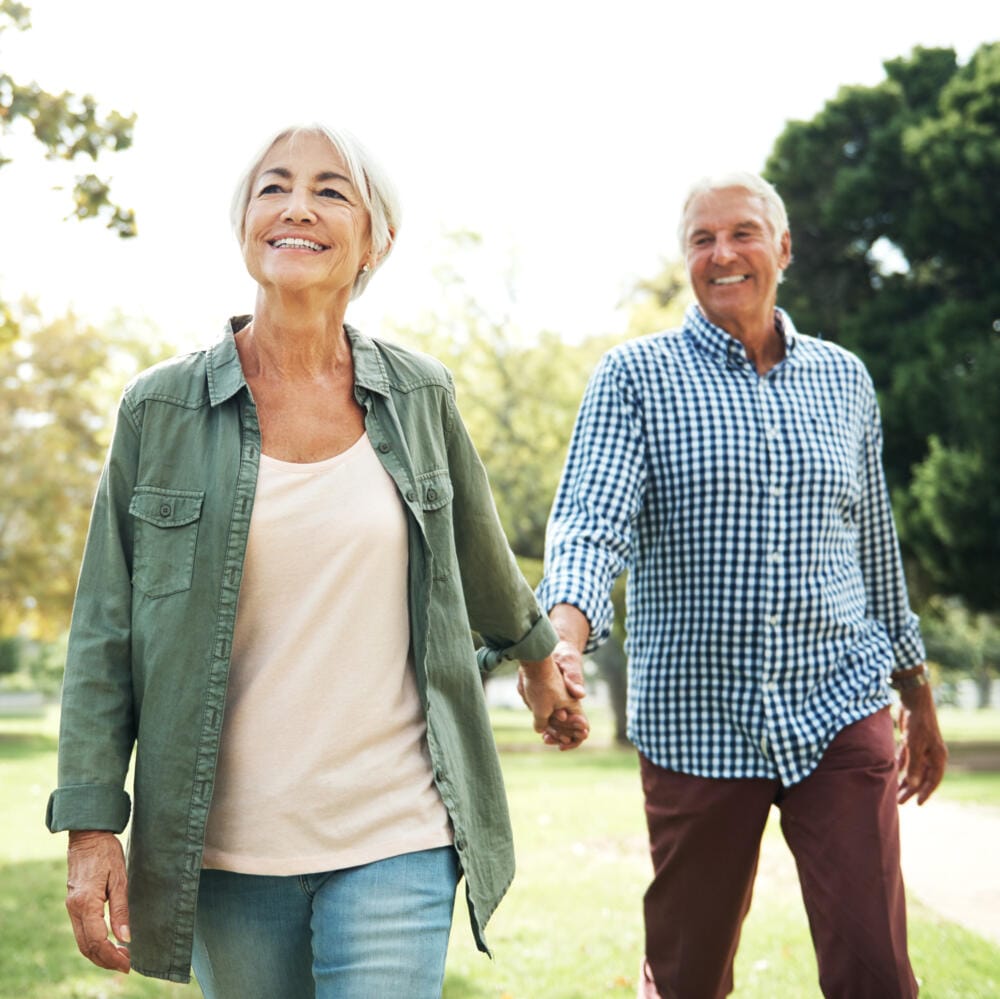 Äldre par går hand i hand i en park