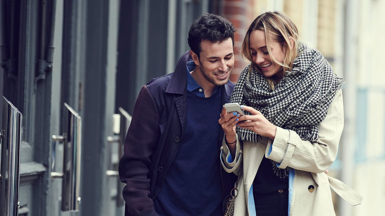 Yngre par tittar ner i en telefon