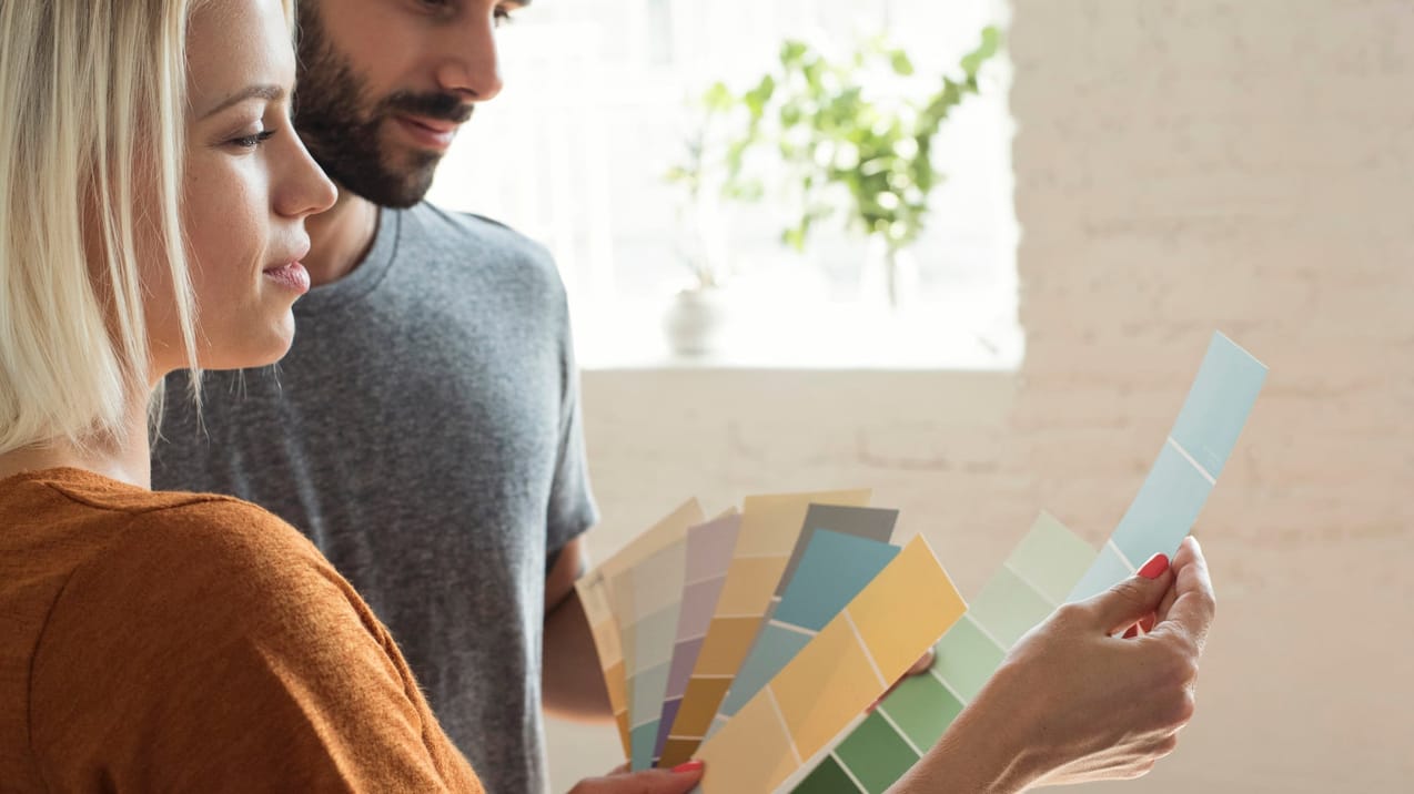 Ett yngre par står och tittar på färgprover