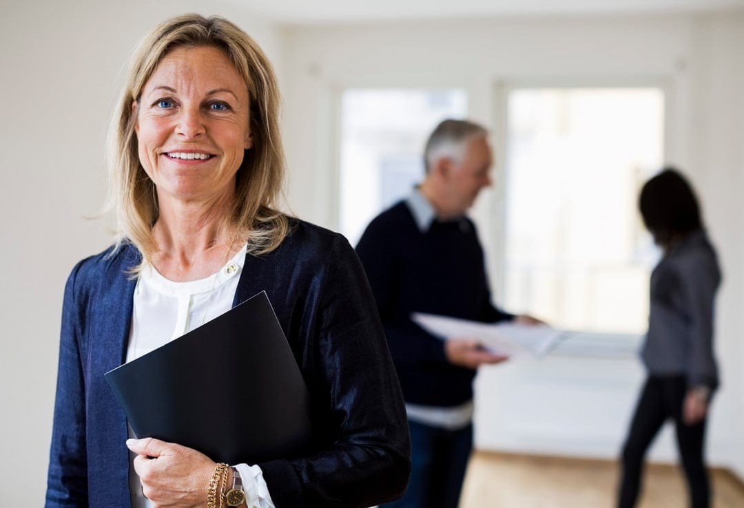 Kvinnlig mäklare står med ett avtal i famnen