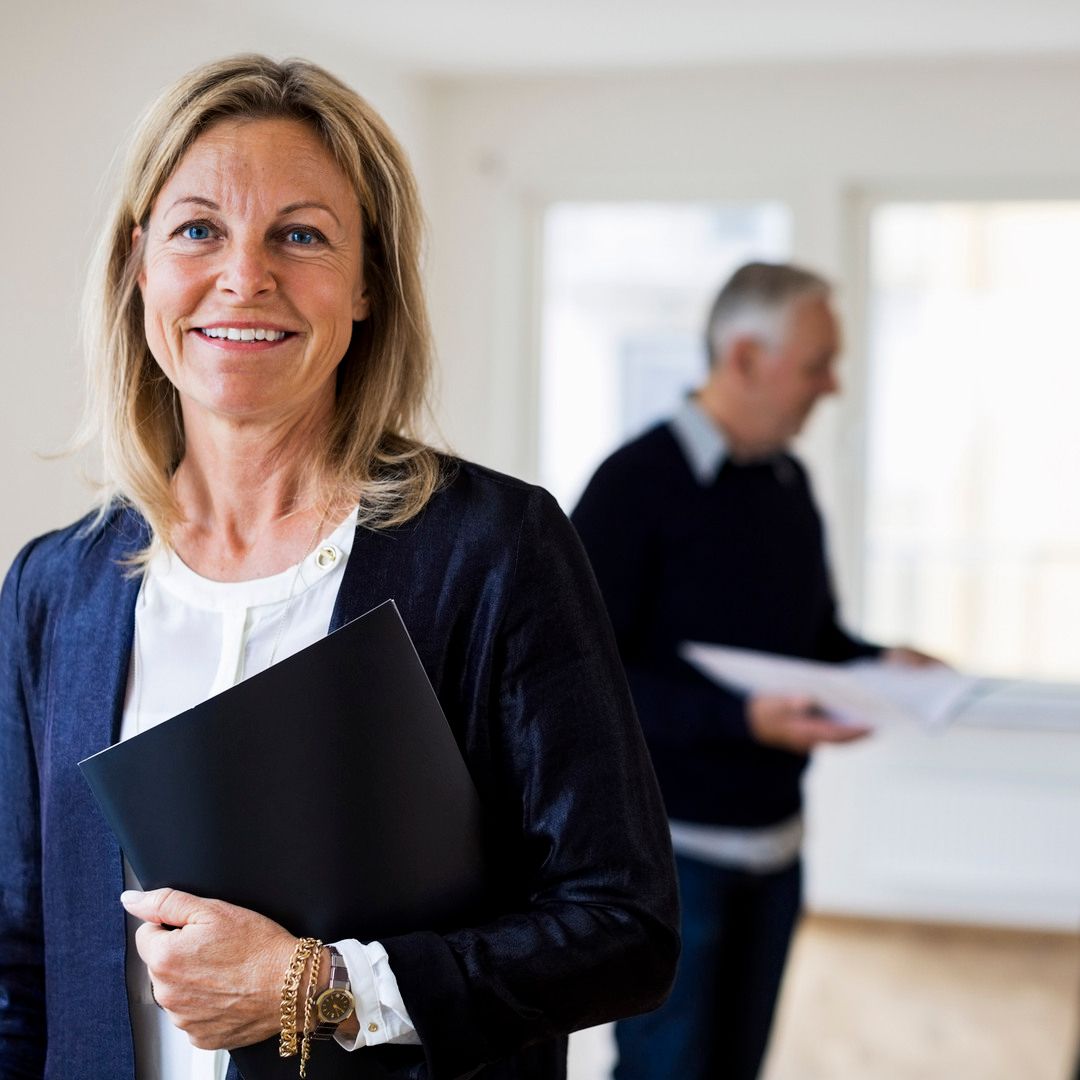 En kvinnlig mäklare som står med ett avtal