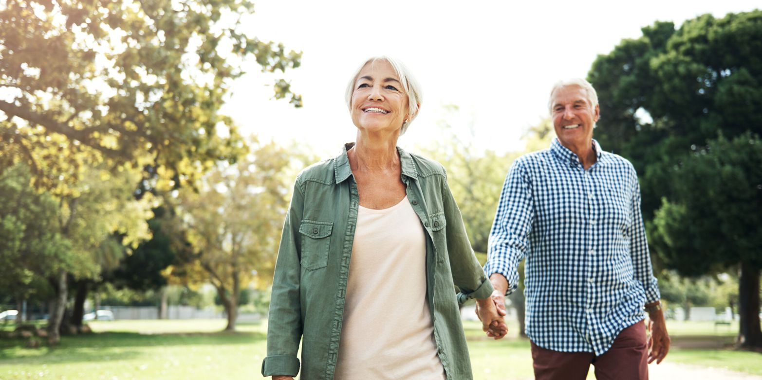 Äldre par går hand i hand i en park