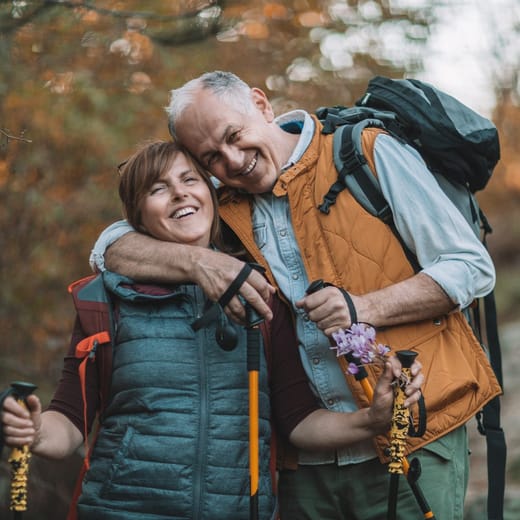 Äldre par är ute och vandrar i en skog