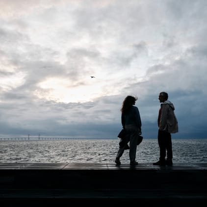 Ett par som står vid havet med Öresundsbron i bakgrunden