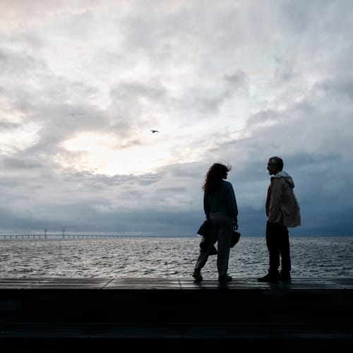 Ett par som står vid havet med Öresundsbron i bakgrunden