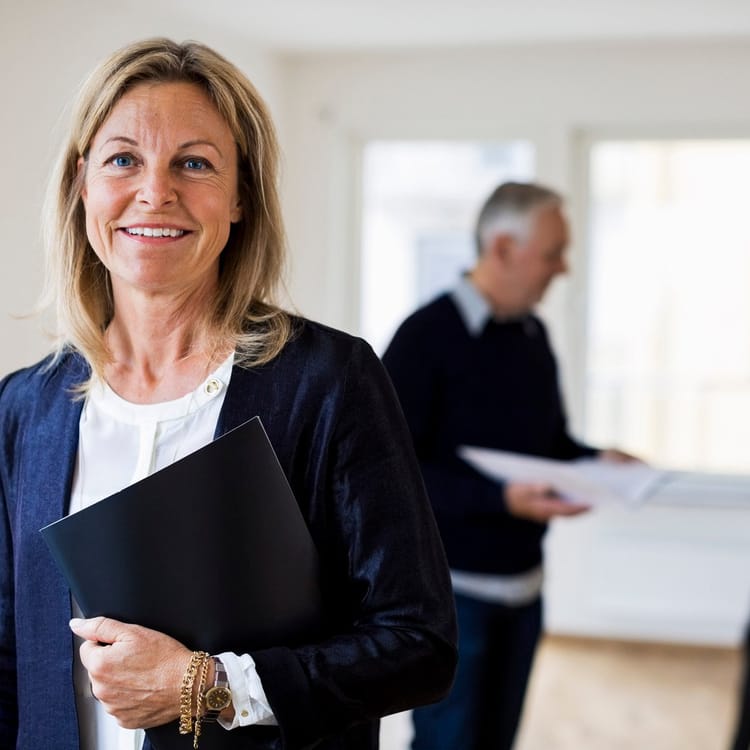 Kvinnlig mäklare står med ett avtal i famnen